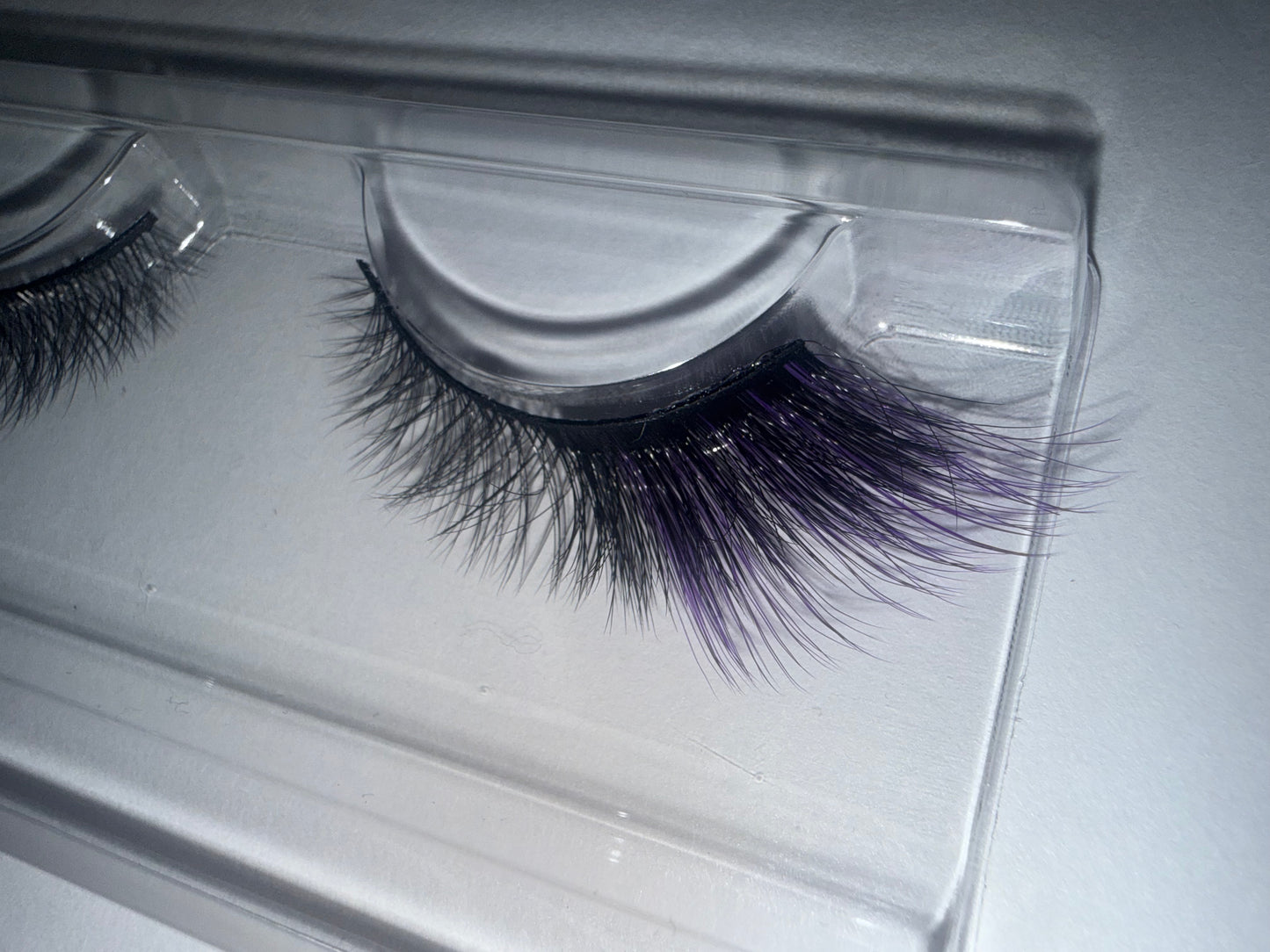 False eyelashes in a clear packaging case on a light gray background