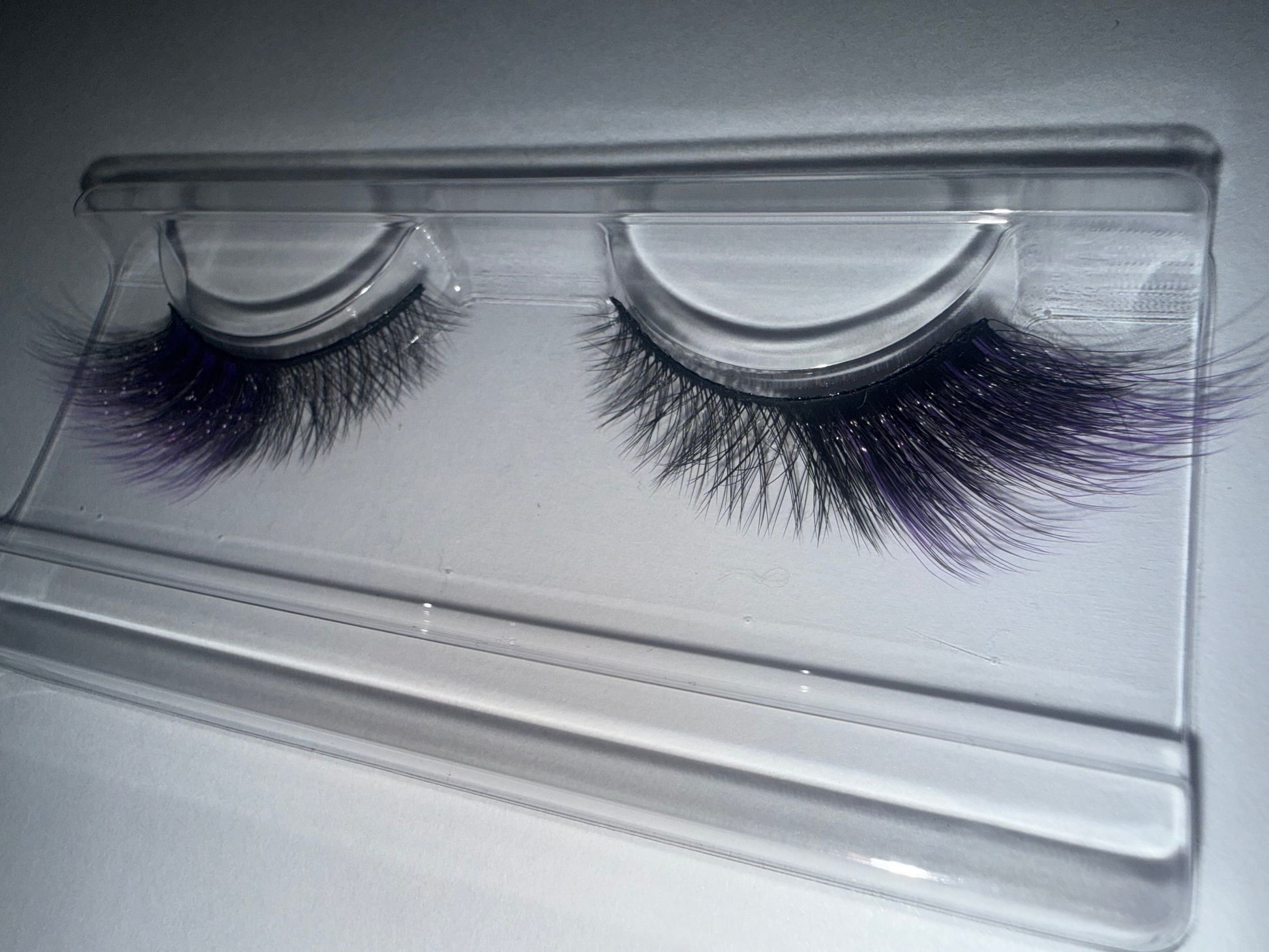 False eyelashes in a clear plastic case on a light gray background